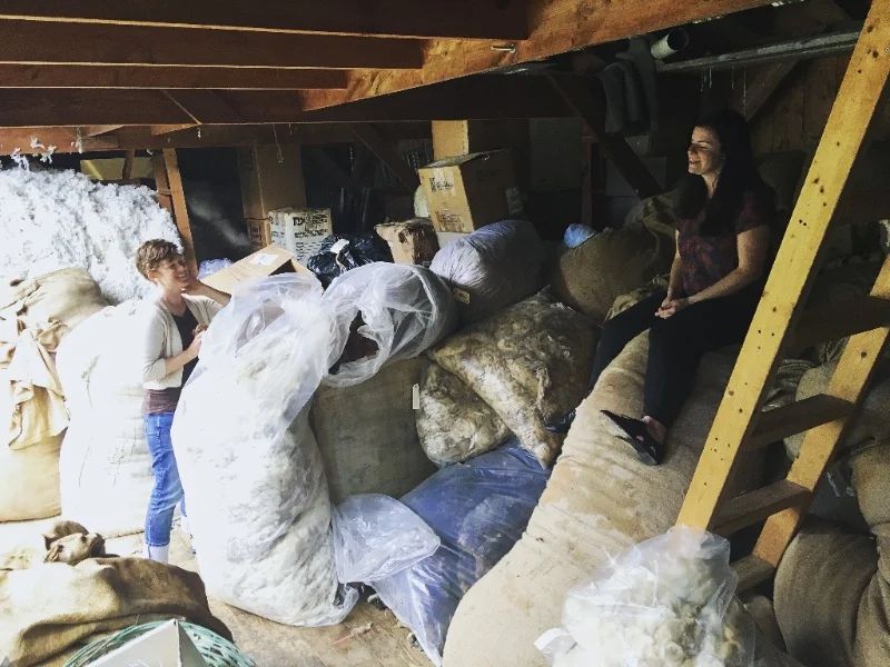 Kate and Hannah in the shed. That bag she's sitting on is our wool.